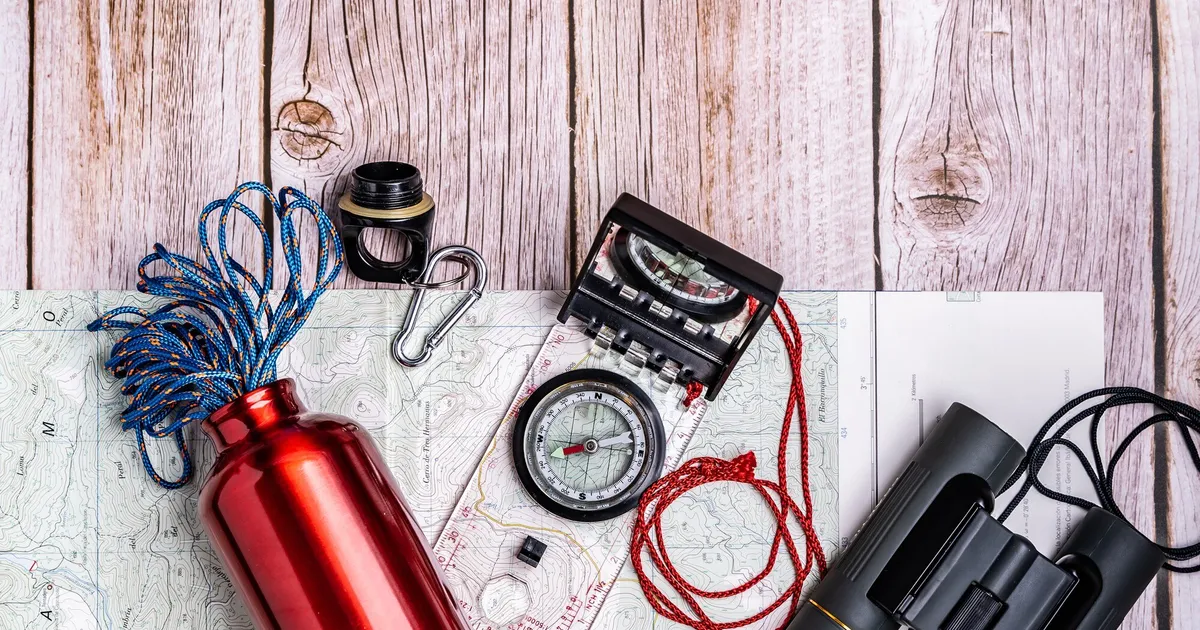 Equipo de supervivencia y material de emergencia organizado sobre mesa de madera para preparar un kit de 72 horas